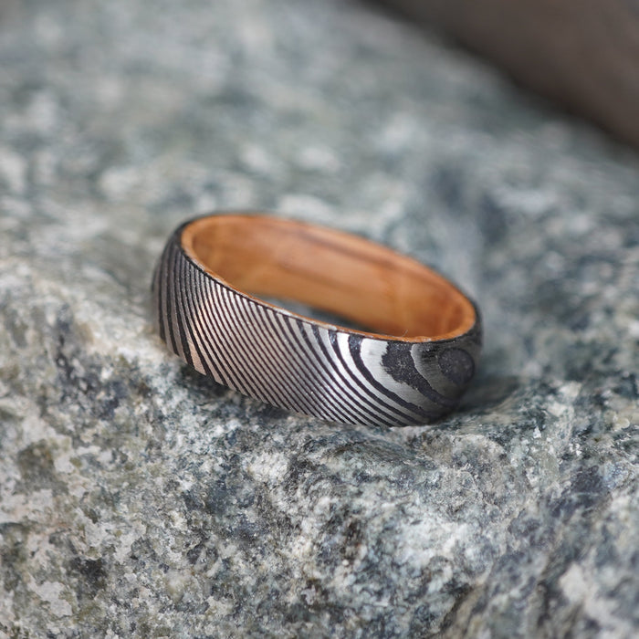 Damascus-style 6mm wedding band with a hammered pattern, featuring a warm interior, by Forge and Lumber.