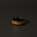 The Fret, an 8mm black plated tungsten band with whisky barrel oak and guitar string inlays