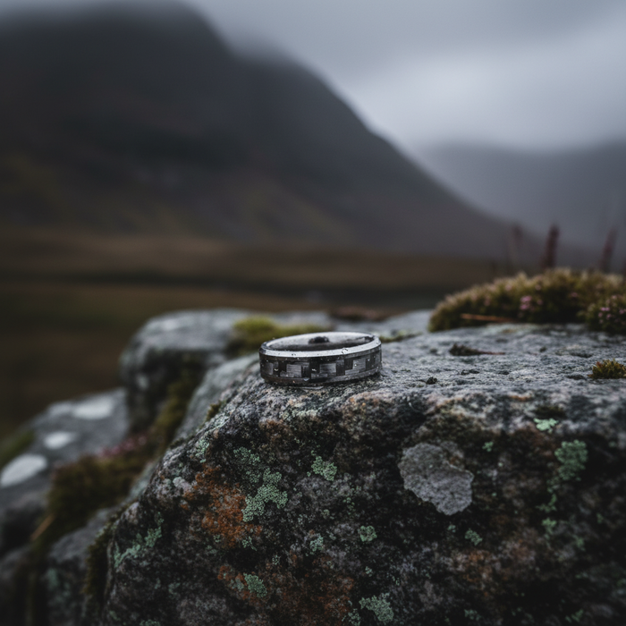 The Weaver 6mm carbon fibre inlay ring on a rocky surface
